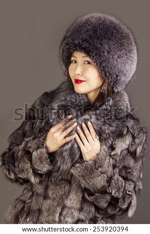 Cute girl oriental appearance in a fur coat and hat from the silver fox