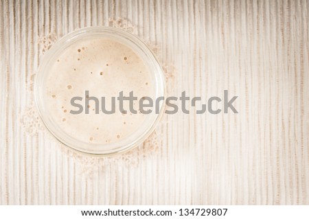 Sourdough in a glass jar on a cream striped table mat with a doily,  top view