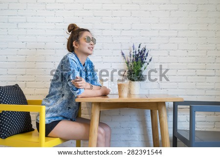 Woman wear blue denim long sleeve shirt and eye glasses with ice coffee drink.