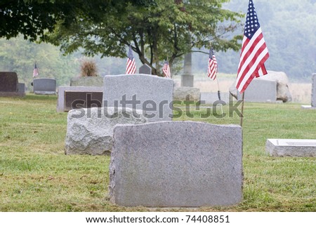 A cemetery with several American flags by the tomb stones
