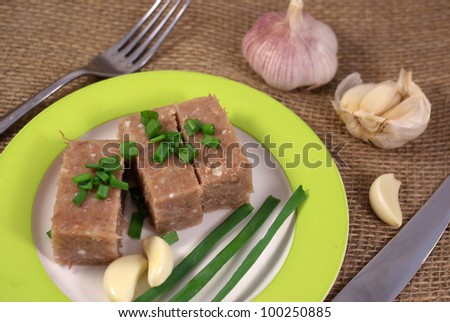 Brawn on a plate on the background of burlap with onion and garlic