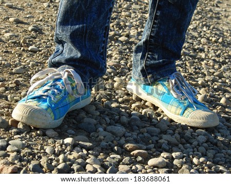 kid legs with gym shoes on stone track.