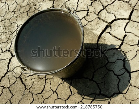bucket full of water on dry soil background