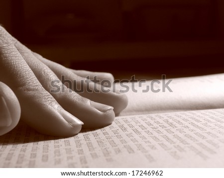 sepia toned fingers pointing at the open book