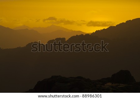 Sunset in the mountains of Corsica. Part of the long distance hike GR20 in France. Yellow skies en clouds. In the distance the sea.
