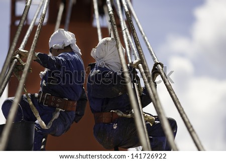 PACIFIC OCEAN - DECEMBER 4, 2008. Seamen grease steel wire of container ship\'s crane. Pacific Ocean on December 4.