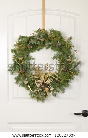 A Christmas wreath on a white door with an agricultural theme