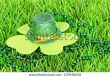 A St Patrick\'s day arrangement with a hat, green beads and shamrock on grass