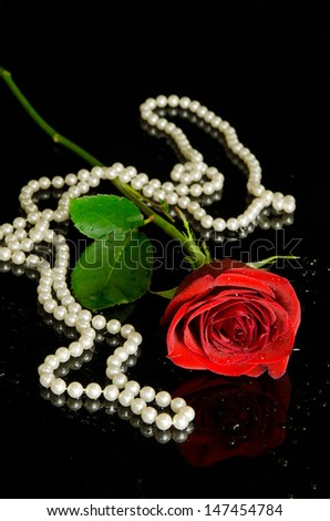 Red rose and pearls on black