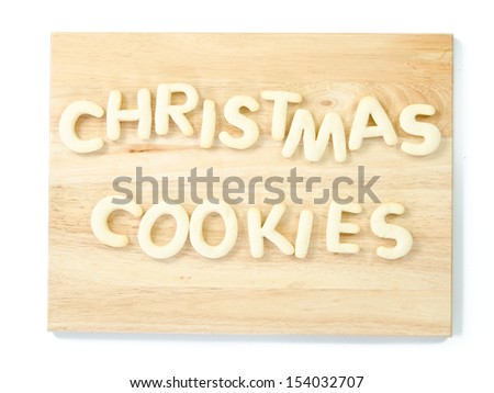 The words Christmas Cookies, spelled of shaped cookies on a wooden cutting board