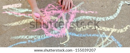 Child\'s hands drawing with chalk on sidewalk