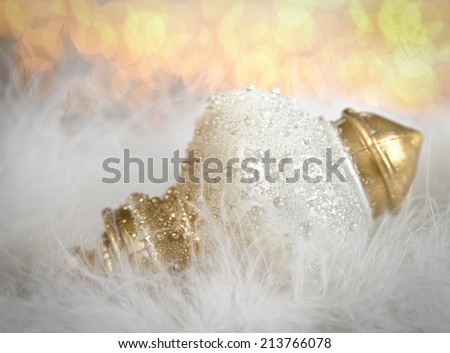 An elegant white and gold Christmas ornament with soft focus lights in the background