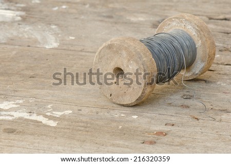 A roll of wire on a weathered wood surface
