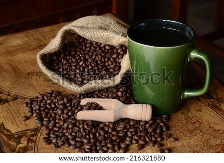 Coffee beans spilling from a burlap bag and a scoop on a textured map surface