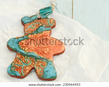 Pottery gingerbread bear tree ornament in rich teals and golds on paper wrapping