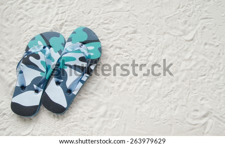 Blue flip flop shoes and on a white sand beach