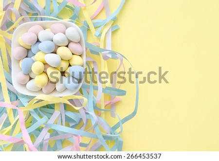 Candy coated chocolate Easter eggs in a white ceramic dish with shredded paper and lots of room for your personal message