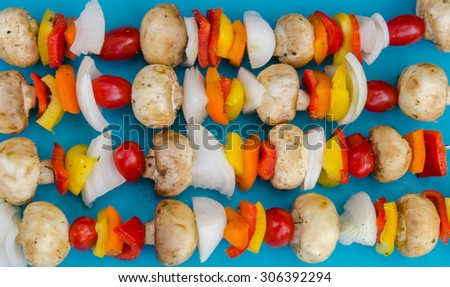 Fresh vegetable kebabs on a blue mat ready to grill