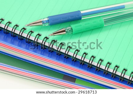 Exercise-books and pens on white background