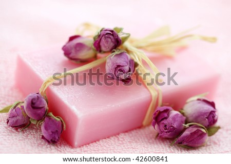 Pink soap with dried roses on towel