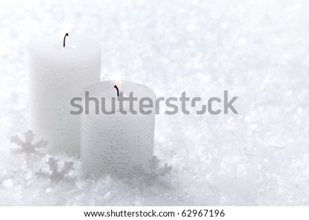 Two white candles on white snow background