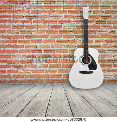 acoustic guitar in empty room with brick wall background