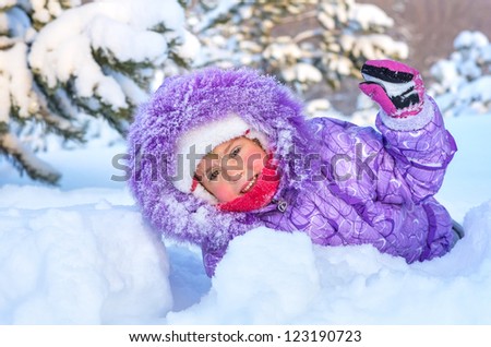 Cheerful little girl playing in a snowy forest. On the face of snowflakes and a drop of water from melting snow.