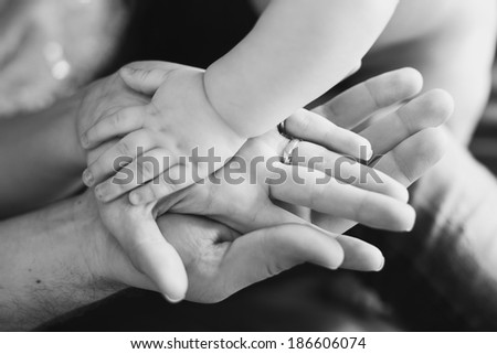Closeup of baby\'s and parent\'s hands. black and white picture