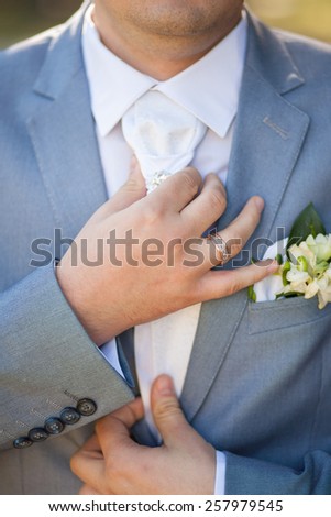 hands of groom in blue suit tying the necktie. unrecognizable man.