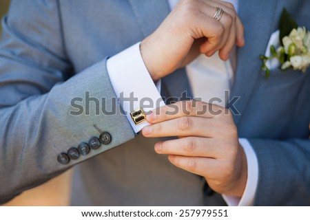 close-up of elegance male hands. man dressed in blue suit and white shirt standing over green nature background. groom in wedding day