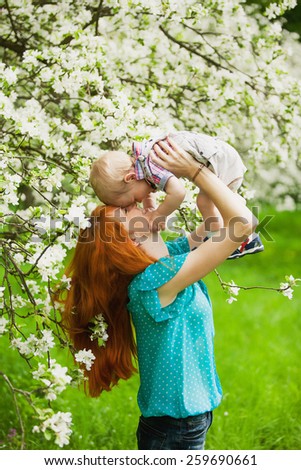 Portrait of happy happy mother ands son in spring garden. They playing and laughing. Blooming apple-trees. Family concept.