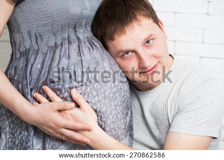 Happy and young pregnant couple hugging. Man and woman expecting for childbirth.Portrait of happy family.