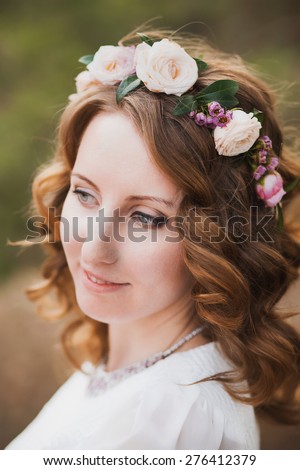 Portrait of beautiful woman with flowers in hair. Young bride. Smiling face of young girl in nature background