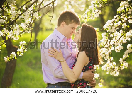 couple in love standing in spring blooming garden. man and woman hugging outside. people face to face portrait. family and love concept.