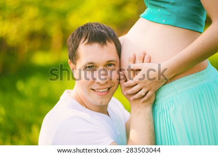 Portrait of father with cheek close to pregnant belly of wife. Pregnant couple. Happy pregnancy. Man and woman. Wife and husband. Young family in expectation of baby. Happy people. New life concept.