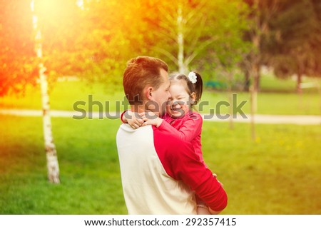 Portrait of a little girl hugging her father outside while having fun together. Happy daddy with daughter playing in summer sunny day.
