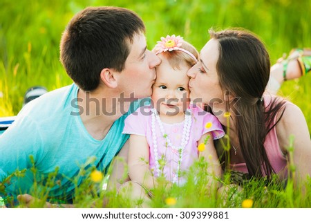 Mom and dad kissing cheeks of little daughter. Family portrait.