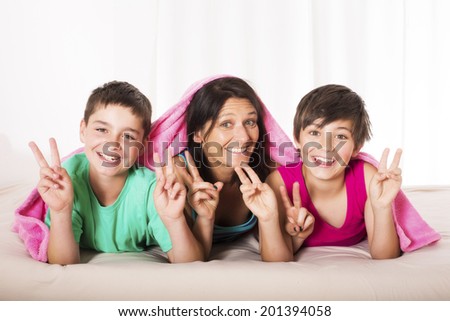 mother and her sons are lying in bed and making the peace sign