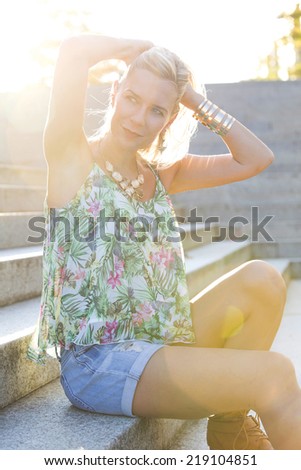blonde woman sitting on stairs in the sun