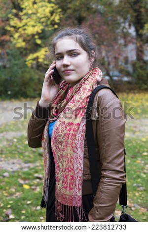 teenage girl standing outside and holding her phone