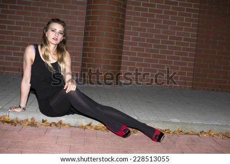 young woman in high heels sitting on a curb in the night