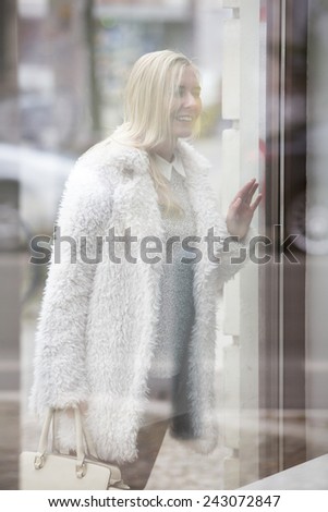 blond woman standing in front of store and looking inside