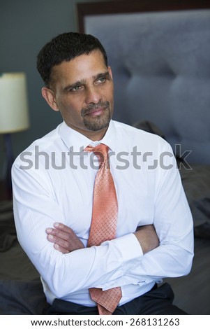 handsome businessman in shirt and tie sitting in bedroom