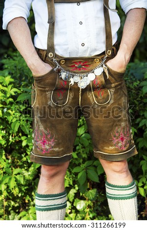 man in traditional bavarian leather pants standing outdoors