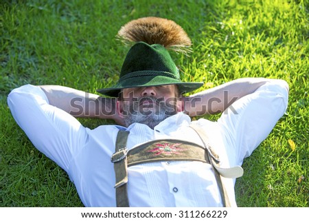man in traditional bavarian clothes sleeping outside in the grass