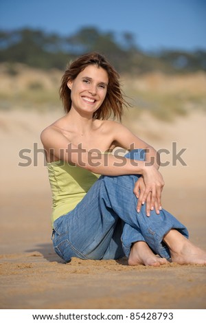 Girl smiling at the beach seated in the sand