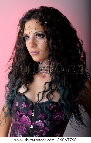 Beautiful brunette woman representing a different style of bride. wearing a black and pink corset, and a tiara and necklace. Studio portrait.