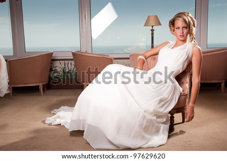 young beautiful blond bride seated on hotel chair