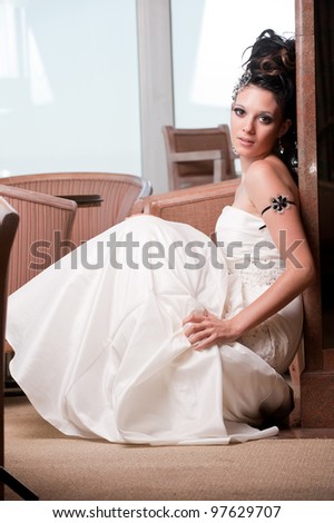 young brunette woman in white dress seated against a wall