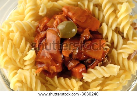 Flaked tuna in a tomato sauce on a noodle and olive on it